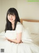 A woman sitting on top of a bed holding a pillow.