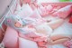 A woman laying on a bed with pink pillows and stuffed animals.