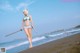 A woman in a bikini holding a sword on the beach.