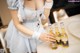 A woman in a maid outfit holding two bottles of beer.