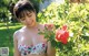 A woman in a floral bikini standing next to a bush.