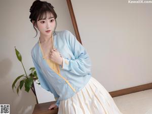 A woman in a blue and white dress posing for a picture.