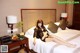A woman sitting on a bed in a hotel room.